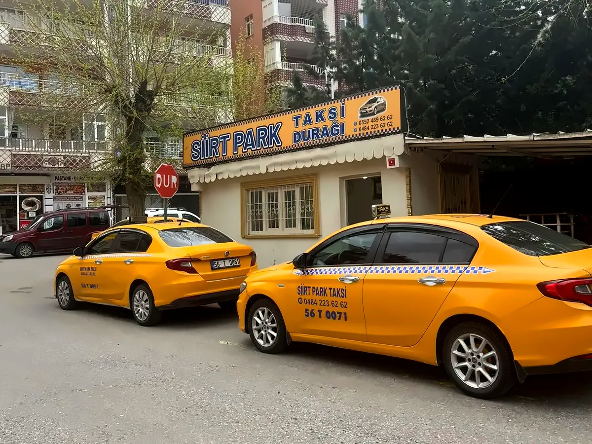 Apartmanların önündeki Siirt Park Taksi Durağı, yanındaki DUR levhası ve iki sarı taksi